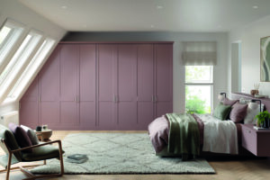 Built-in Basel door Superior Matt Antique Rose (light dusky pink) wardrobe with long vertical handles, fitted into a sloped ceiling bedroom