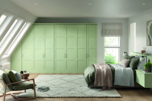 Built-in Lanark door Matt Meadow Green wardrobe with long vertical handles, fitted into a sloped ceiling bedroom