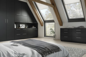 Built-in Vilo Serica door Graphite (black) wardrobe with multiple cabinets, fitted into a sloped ceiling bedroom with exposed wooden beams.