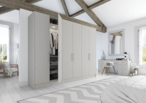 Contemporary bedroom with Vivo Matt wardrobe doors in light grey, showing organized clothes and shoe and a wood-accented desk with mirror