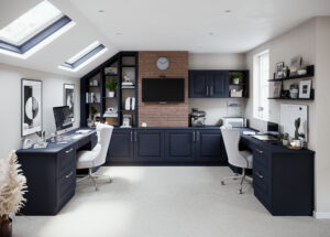 Dual-station home office,  under a slanted ceiling with skylights, featuring built-in with Portree cabinets in Indigo (dark blue) and an exposed brick wall